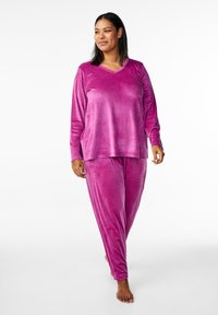 Completo in tessuto morbido e rosa composto da top a maniche lunghe e scollatura a V, accompagnato da pantaloni. Caratterizzato da una vestibilità comoda e una texture liscia, ideale per il comfort e il relax.