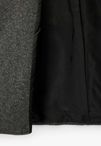 Grauer Außenstoff mit strukturierter Oberfläche, schwarzes Innenfutter; langer Mantel mit klaren Nähten und ohne sichtbare Beschläge.