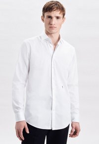 Witte overhemden met lange mouwen, gemaakt van een gladde stof, voorzien van een puntkraag, een subtiel logo aan de onderzijde en een slim fit.