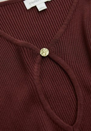 Maglione bordeaux a coste con scollatura a V e un bottone dorato rotondo e texturizzato che accentua la parte frontale. Realizzato in morbido tessuto a maglia e con un design aderente.