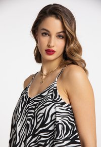 Schwarzes und weißes Zebra-Muster-Camisole mit dünnen Trägern; glattes Gewebe; niedriger Rundhalsausschnitt; geschichtetes Design; kombiniert mit geschichteten Halsketten in Goldton.
