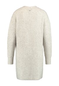 Ljus beige stickad tröja med avslappnad passform, ribbat mönster och långa ärmar. Har en rundad halsringning och en något längre nederkant bak.