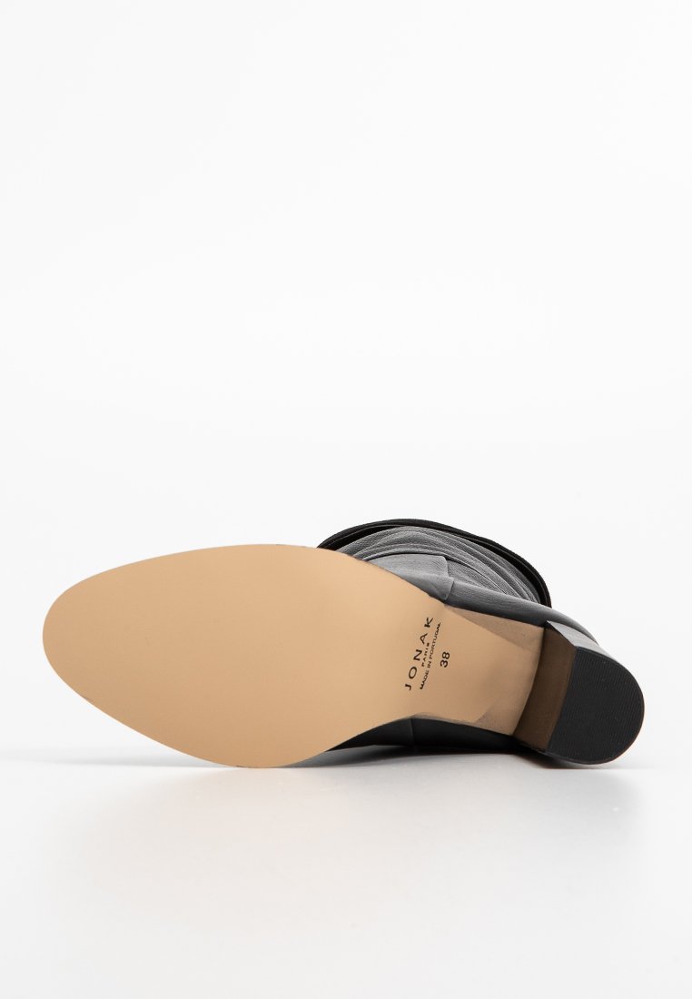 Semelle d'une bottine noire avec un fond en cuir beige, talon empilé, et le nom de la marque "JONAK" et la taille 38 imprimés sur la semelle.