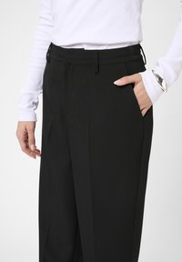 Sorte skræddersyede bukser med en glat tekstur, der har sidelommer, et lige ben-design og en flad talje.