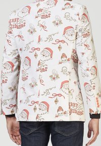 Witte blazer met een speelse kerstthema patroon van kerstman gezichten, mistletoe en ornamenten. Versierd met roze knopen.