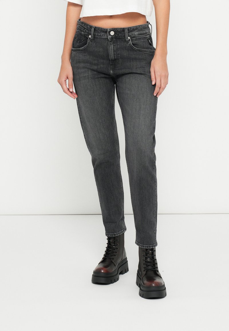 Magas derekú, slim-fit szürke farmerszínű farmerek. Ötpocketes kialakítás gombos záródással. Vastag fekete fűzős csizmával párosítva.