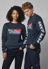 Los sudaderas de color azul oscuro presentan un logotipo audaz en rojo y blanco en la parte frontal. "PEPE JEANS" está impreso en blanco en las mangas.