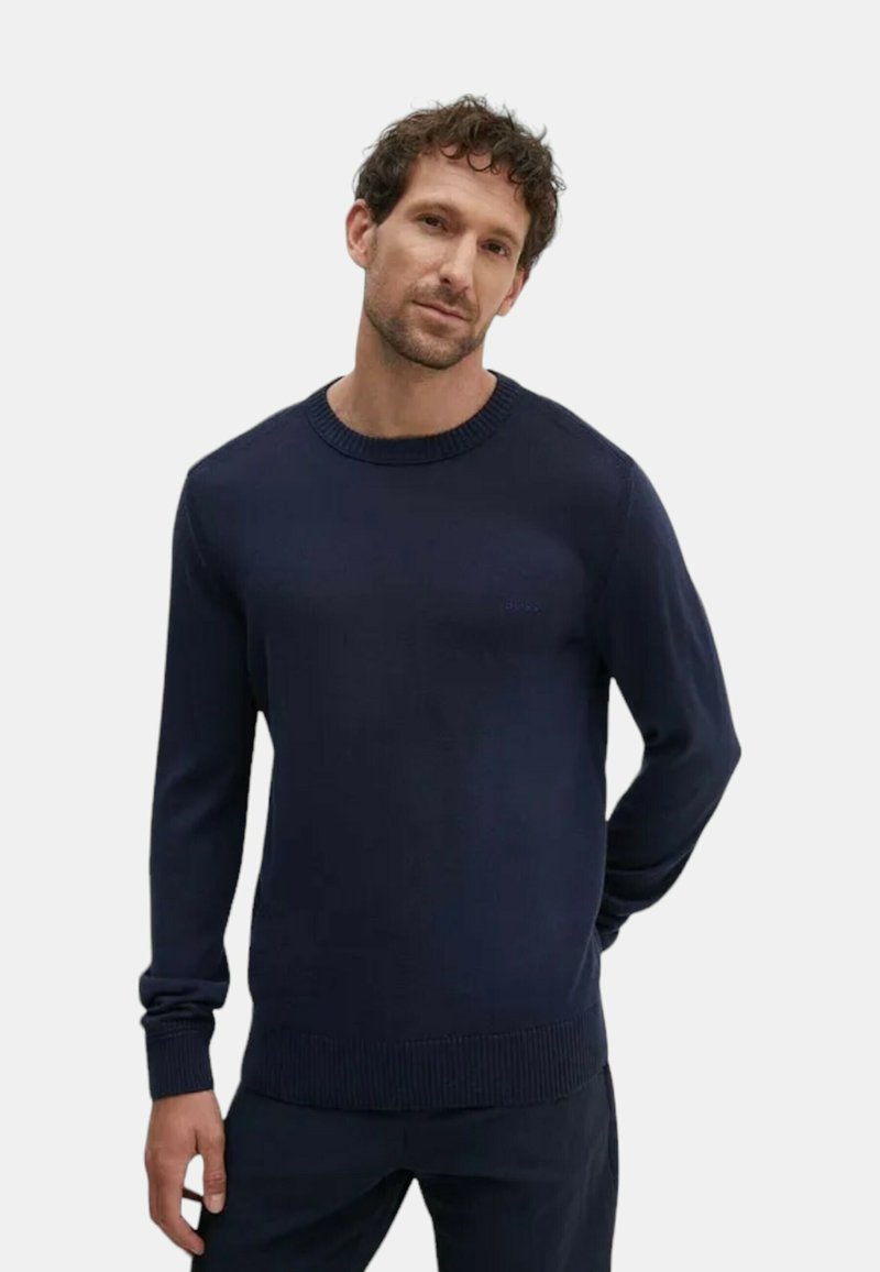 Pull en maille bleu marine avec un col rond, des poignets et un ourlet côtelés. Texture lisse avec un logo subtil de la marque sur la poitrine.
