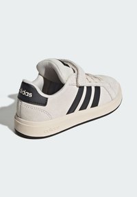 Lichtcreme suède sneakers met zwarte leren strepen en branding, voorzien van een klittenbandsluiting en een beige rubberen zool voor grip.