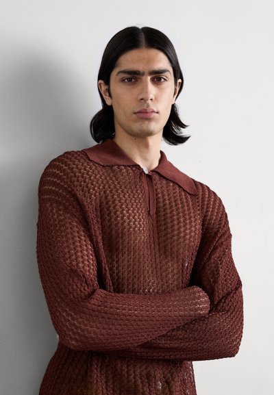 Pullover lavorato a maglia di un rosso scuro con un motivo testurizzato, dotato di colletto e chiusura a bottoni. Maniche lunghe con polsini affusolati.