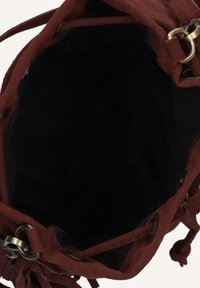 Bruine suede tas met een zachte textuur, ontwerp met een open bovenkant en zwarte binnenvoering; voorzien van goudkleurige hardware en decoratieve franjes.