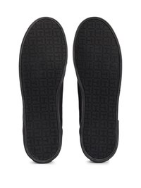 Black sneakers with a textured rubber sole featuring a geometric pattern, showing the bottom view with rounded edges and no visible logos.