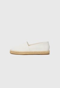 Bijela platnena espadrila s tkanim jute potplatom i šivenim detaljima, koja ima dizajn na vezivanje i minimalistički stil.