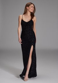 Abito da sera nero in paillettes con scollatura a cascata, vestibilità aderente e spacco alto fino alla coscia. Presenta sottili spalline e una superficie liscia.