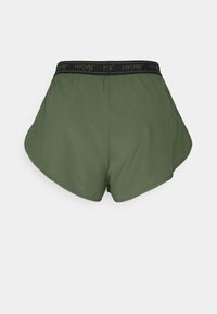 Gröna shorts med ett svart elastiskt midjeband som har "HKMX"-logotypen. Stretchigt material och en rundad nederkant med slät textur.