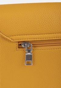 Borsa in pelle gialla testurizzata con una tasca con zip e dettagli in metallo argentato. Presenta una finitura liscia e linee di design pulite.