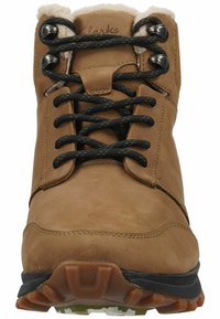 Bota de senderismo de cuero marrón con cordones negros, cuello de felpa y suela de goma. Presenta una puntera resistente y ojales reforzados.
