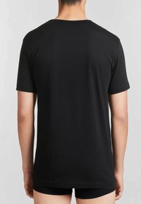 T-shirt nera in cotone con maniche corte, dotata di colletto rotondo e una consistenza liscia. Il design è semplice e senza decorazioni.