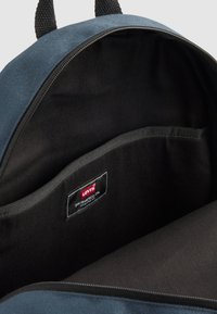 Levi's nahrbtnik z modrim zunanjim delom, črno notranjo oblogo, glavno zanko in oznako znotraj žepa. Zipper zapiranje.