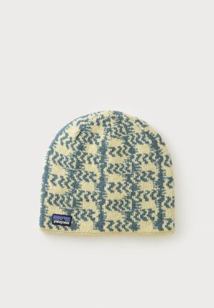 Gebreide Patagonia beanie in crème met turquoise geometrisch patroon en merklogo-label aan de onderkant tegen een witte achtergrond.