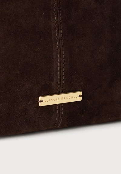 Καφέ σουέντ τσάντα χειρός με κάθετη ραφή, διακοσμημένη με πλάκα λογότυπου σε χρυσό μέταλλο. Ομαλή υφή με ματ όψη.