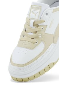 Sneaker PUMA con una colorazione bianca e beige, con una tomaia in pelle liscia, dettagli testurizzati e una suola in gomma spessa con un battistrada a motivi.