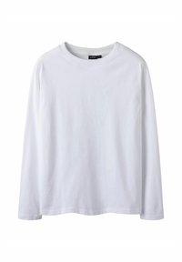 Biała koszulka z długim rękawem wykonana z bawełny. Posiada okrągły dekolt, prosty krój oraz delikatne wygięcie na dole dla luźniejszego fasonu.