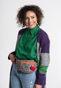 Szary, fioletowy i zielony kardigan w paski na zielonej koszuli z kołnierzykiem. Model nosi szary, teksturowany nerki z pomarańczowym suwakiem i czerwonym akcentem.