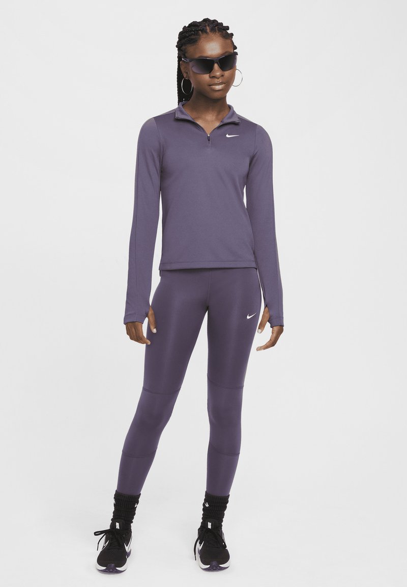 Maglia a maniche lunghe viola con zip e leggings abbinati in tessuto elasticizzato. I dettagli notevoli includono un piccolo logo bianco sul petto e sneakers nere.