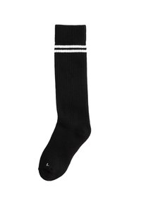 Calza nera a coste fino al ginocchio con strisce bianche nella parte superiore. Presenta una punta rinforzata e un'etichetta che indica la taglia "L."