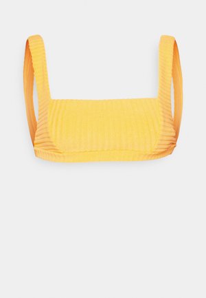 Gul randig kort top med breda axelremmar, fyrkantig halsringning och textil med horisontella linjer genomgående.