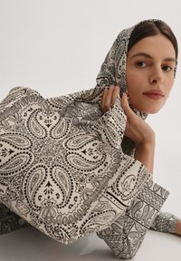 Torebka na ramię z wzorem, wykonana z bawełny, w monochromatyczny wzór paisley. Posiada mocne uchwyty oraz wyraźny kształt ułatwiający noszenie.