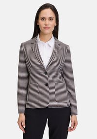 Blazer confectionné dans un tissu texturé, présentant un motif noir et blanc, des revers à cran, deux boutons sur le devant et des poches à rabat.