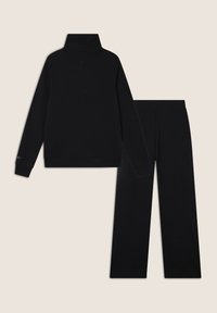 Maglione a maniche lunghe nero con colletto a dolcevita e pantaloni larghi coordinati, entrambi realizzati in materiale morbido con cuciture minime e senza motivi visibili.