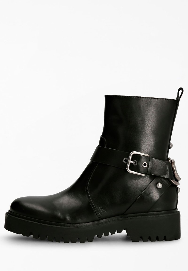 Bottine en cuir noir à finition lisse, avec un accent de boucle et une semelle robuste. Présente un design élégant et une languette à l'arrière.