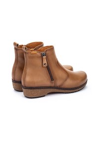 Bottines en cuir marron avec fermetures éclair sur les côtés et semelles en caoutchouc texturé, présentant un talon bas recouvert de liège et une surface lisse.