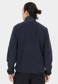 Marineblauwe fleece pullover met gestructureerde mouwen, hoge kraag en een gladde body. Heeft een relaxte pasvorm en gestikte naden.