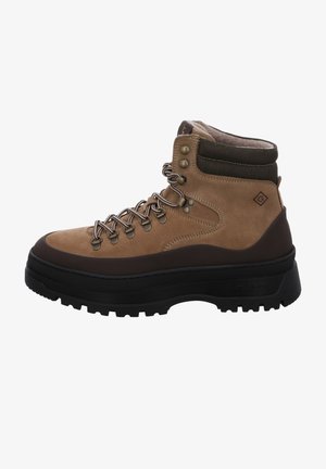 Botte de randonnée en daim marron avec semelle épaisse noire, œillets métalliques, col rembourré et lacets beige à motifs noirs.