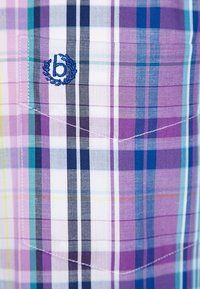 Camisa de cuadros con colores púrpura, azul y blanco. Material de algodón, estilo con botones y logo bordado en el bolsillo del pecho.