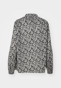 Chemise noire à manches longues avec un motif floral blanc, col classique et poignets boutonnés, présentée de dos sur fond blanc.