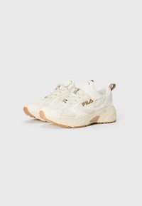 Hvite joggesko med nettpaneler, gummisåler og borrelås. Utsmykket med beige detaljer og Fila-logo på siden.