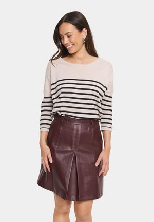 Beige og sort stribet sweater med trekvartærmer, parret med en bordeaux læderskørt med en frontplissering og bæltestropper.