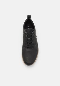 Black sneaker in leather with a textured upper. Features round laces, eyelets, and a pull tab. Size 43, with a contrasting rubber sole.
