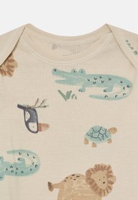 Light beige baby onesie featuring colorful animal motifs, including a crocodile, turtle, and lion. Soft cotton fabric with short sleeves.