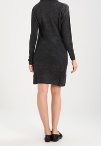 Robe en maille gris foncé, avec un col montant, des manches longues, et une coupe décontractée, avec un ourlet juste au-dessus du genou. Texture lisse.