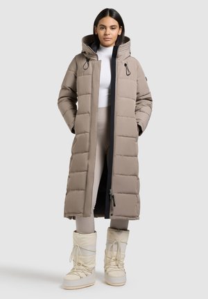 Hea pruun pehme pikk jakk kapuutsiga, millel on ees lukk ja nööristetailid. Koos valgete, lipsuga talvekingadega.