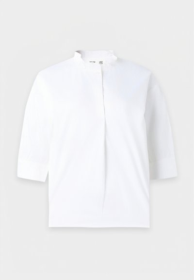 Blouse blanche avec manches trois-quarts et petit col montant, patte de boutonnage dissimulée à l'avant, design uni.