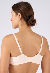 Sostén de color rosa claro con tela texturizada, tirantes ajustables y bordes con forma de onda. Cuenta con un cierre de gancho y ojo en la parte posterior para un ajuste seguro.