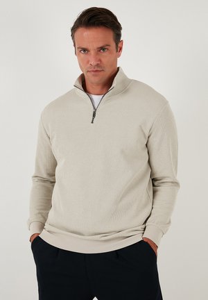 Lichtbeige quarter-zip pullover van ribstof, met een hoge kraag, lange mouwen en contrasterende manchetten met zijzakken.