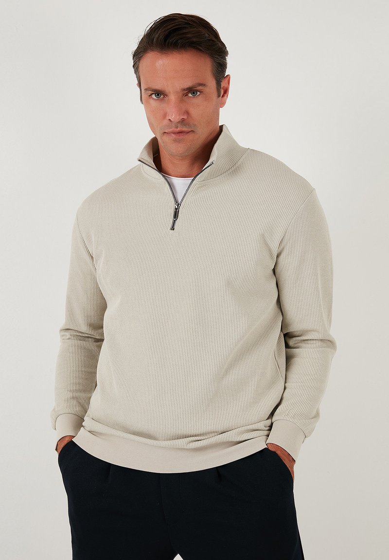 Helebeež värvi veerandzip pullover, mis on valmistatud soonikkangast, kõrge kraega, pikkade varrukatega ja kontrastsete mansettidega, küljetaskutega.